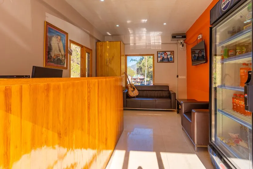 Reception with a wooden counter, seating and a cold drinks cabinet
