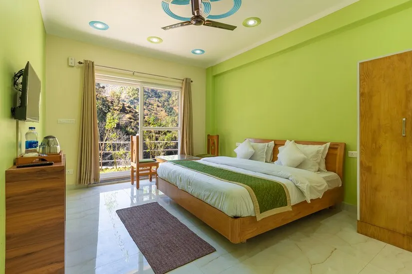Grand Room with a king bed, wardrobe, television, tea tray and balcony doors onto the hillside
